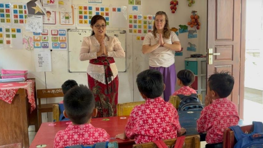 Lynn staat samen met een indonesische docente voor de klas met kleuters in schooluniform
