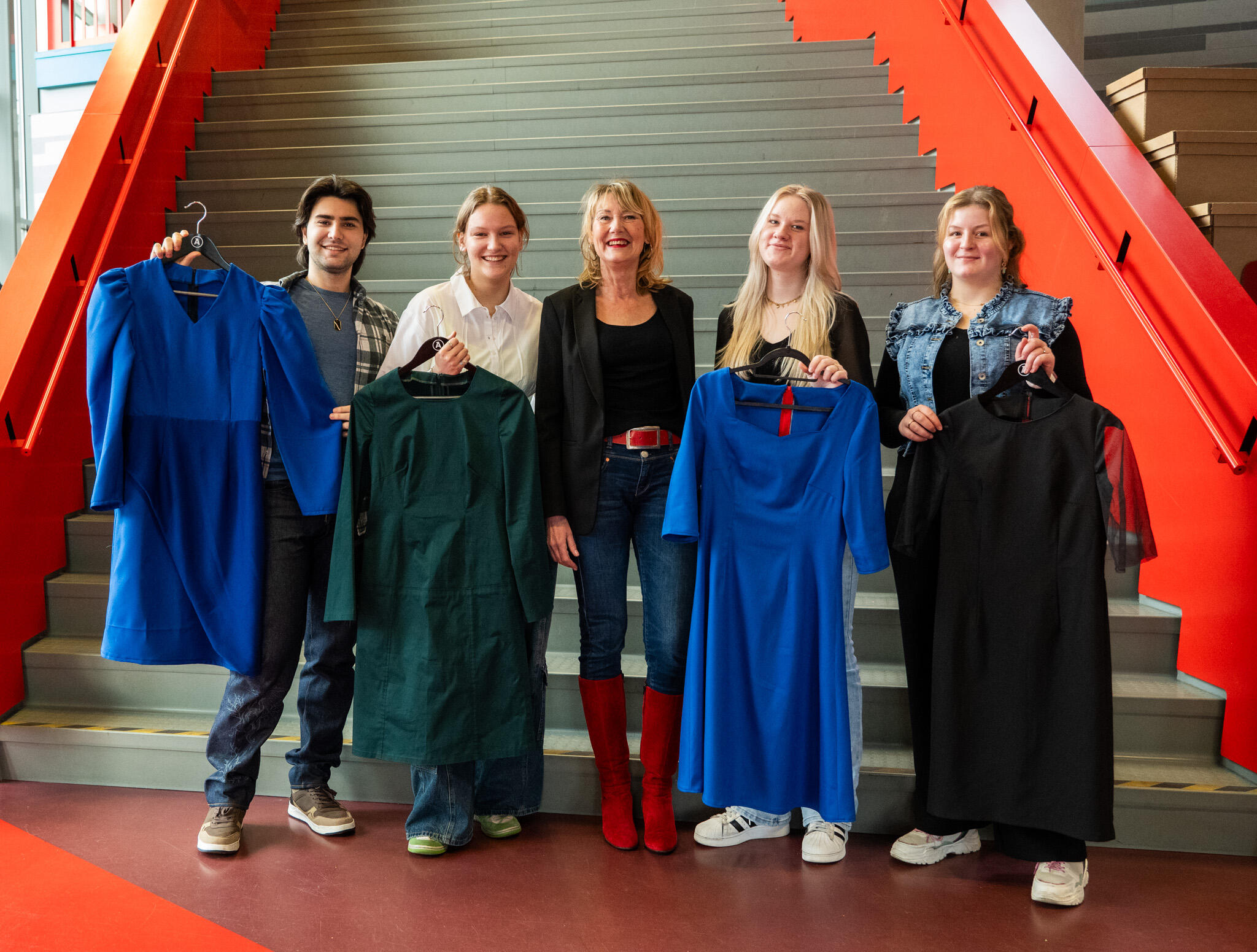 Vier tweedejaarsstudenten van de opleiding Fashion tailor poseren met hun kledingstuk met Ellen Marks