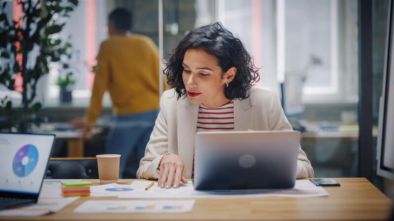 dame op kantoor met een laptop die grafieken bekijkt