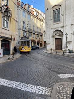 Straatbeeld van Lissabon met een tram die een straat binnenrijdt