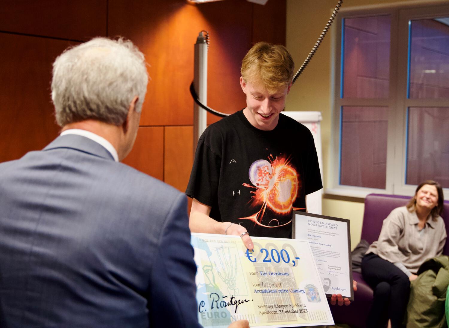 Een winnaar van de Röntgen Award ontvangt blij de cheque ter waarde van € 200