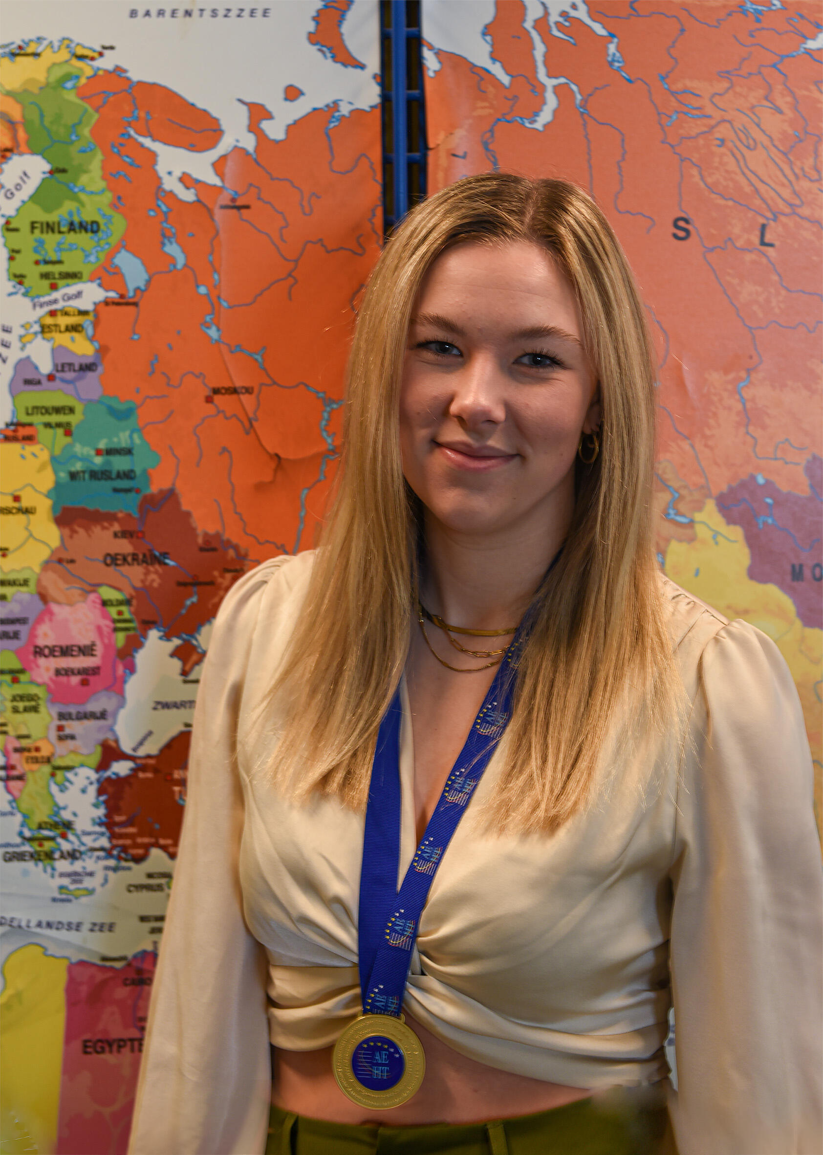 Aventus-student Laura van de opleiding Leidinggevende Travel & Hospitality staat met een met een gouden medaille om voor de kaart van Europa
