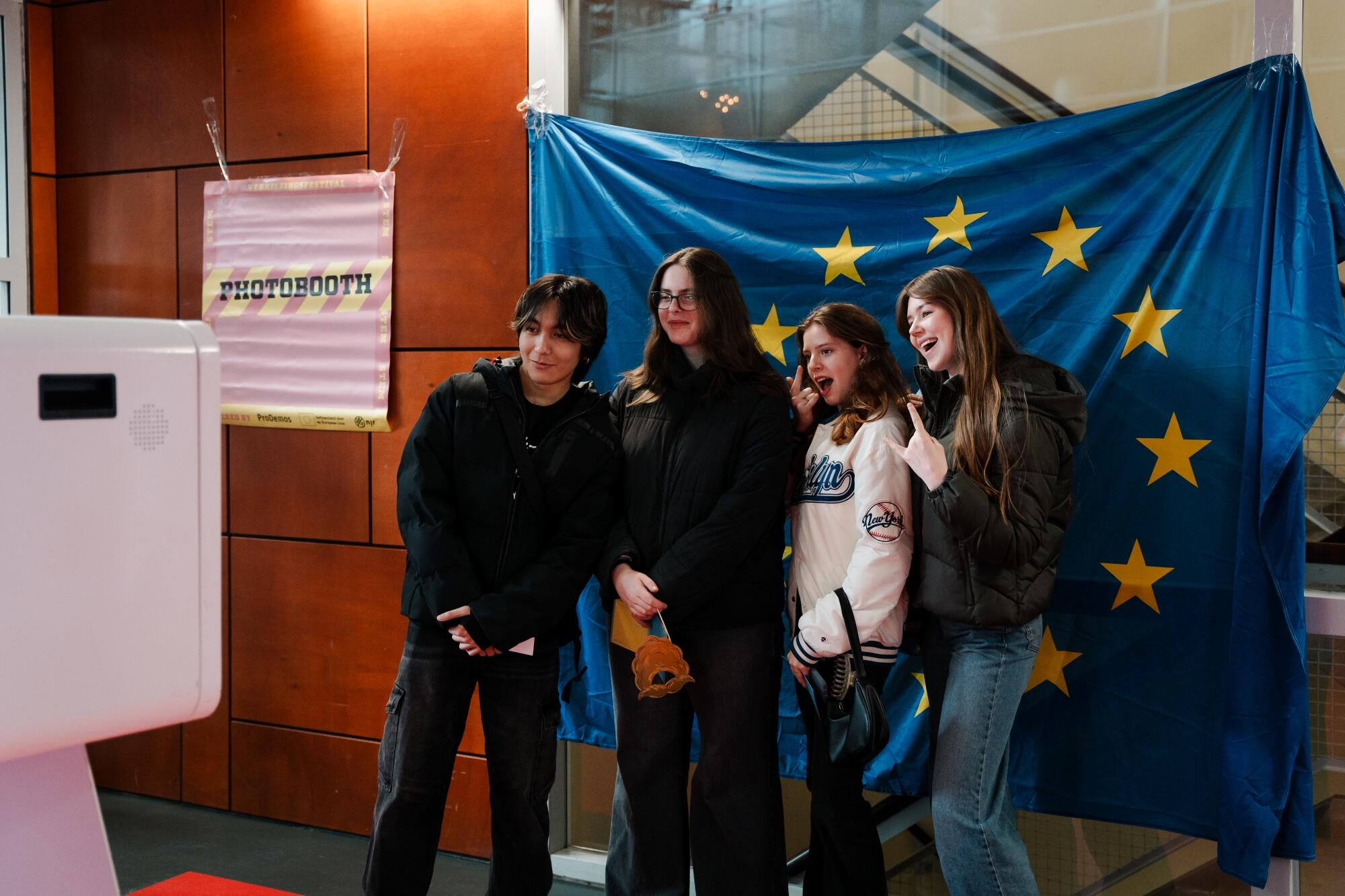Vier jongere staan voor de Europese vlag tijdens het Verkiezingsfestival 2024