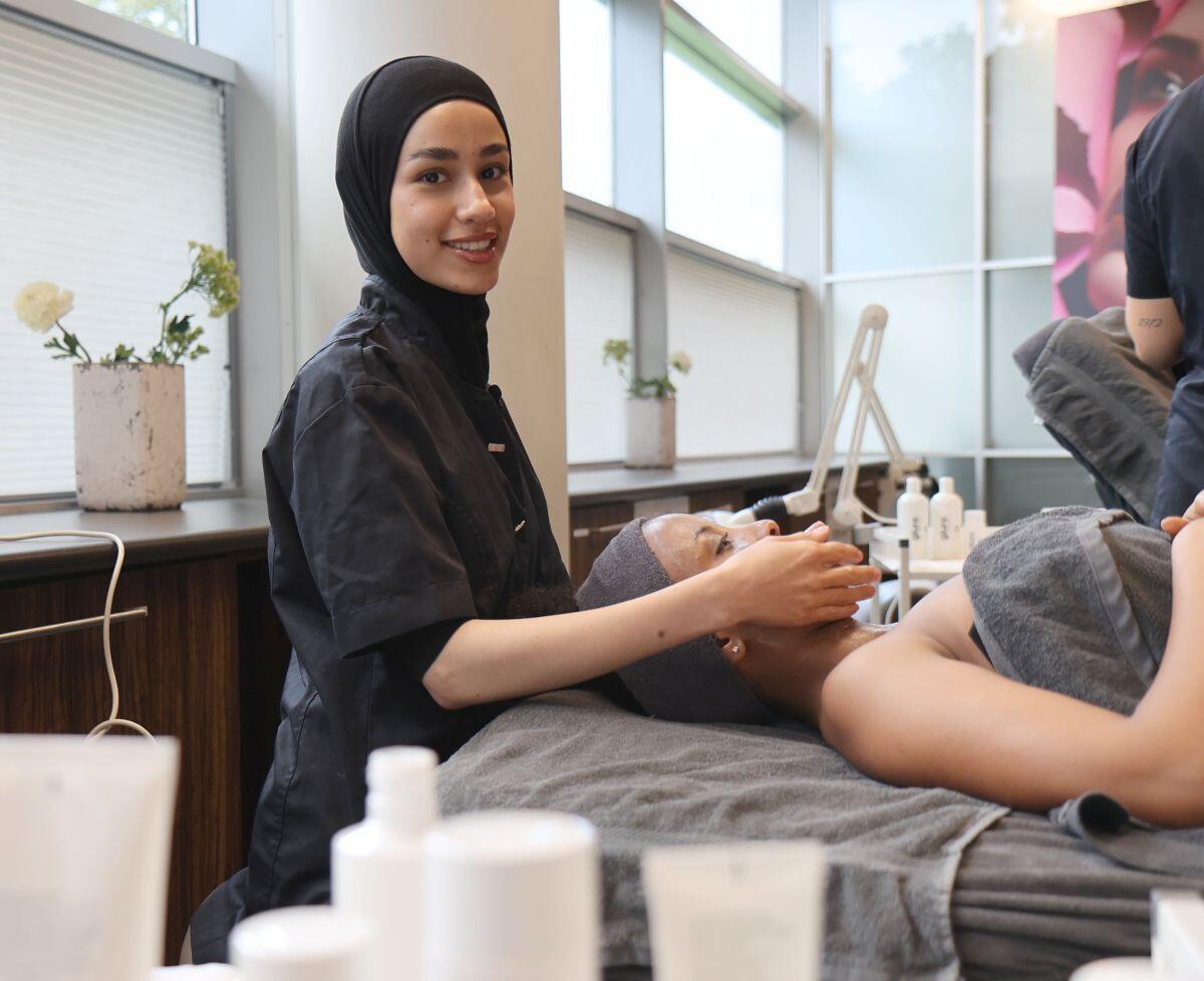 Een jongedame geeft een gezichtsbehandeling aan een klant