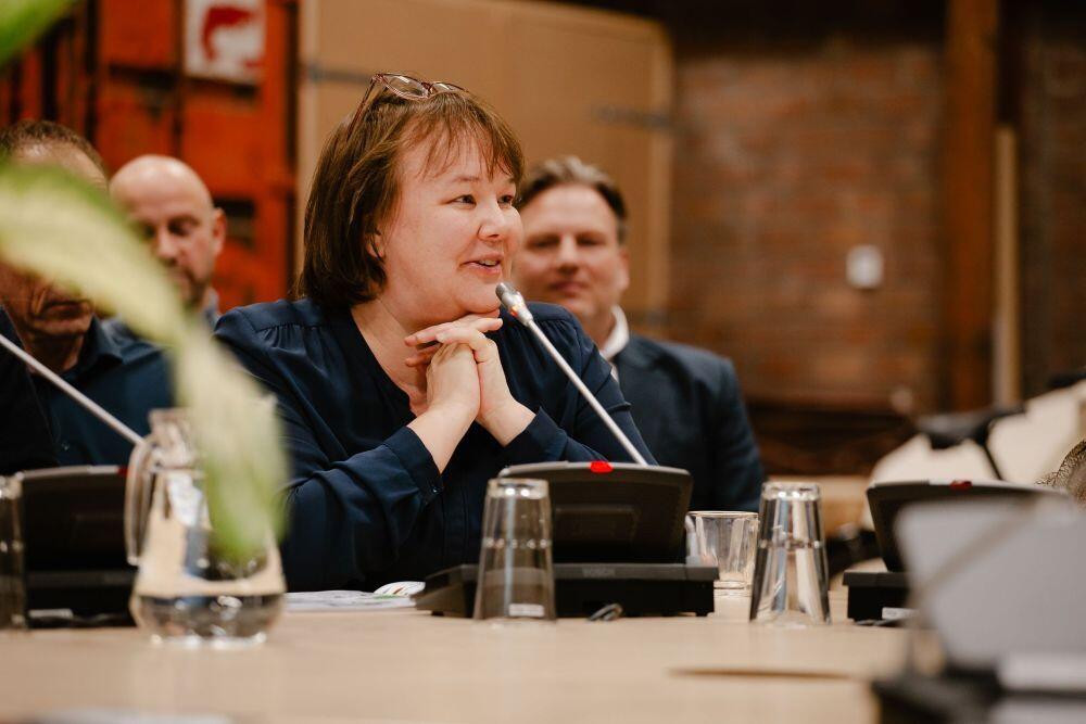 Een dame zit aan een tafel en praat in een microfoon