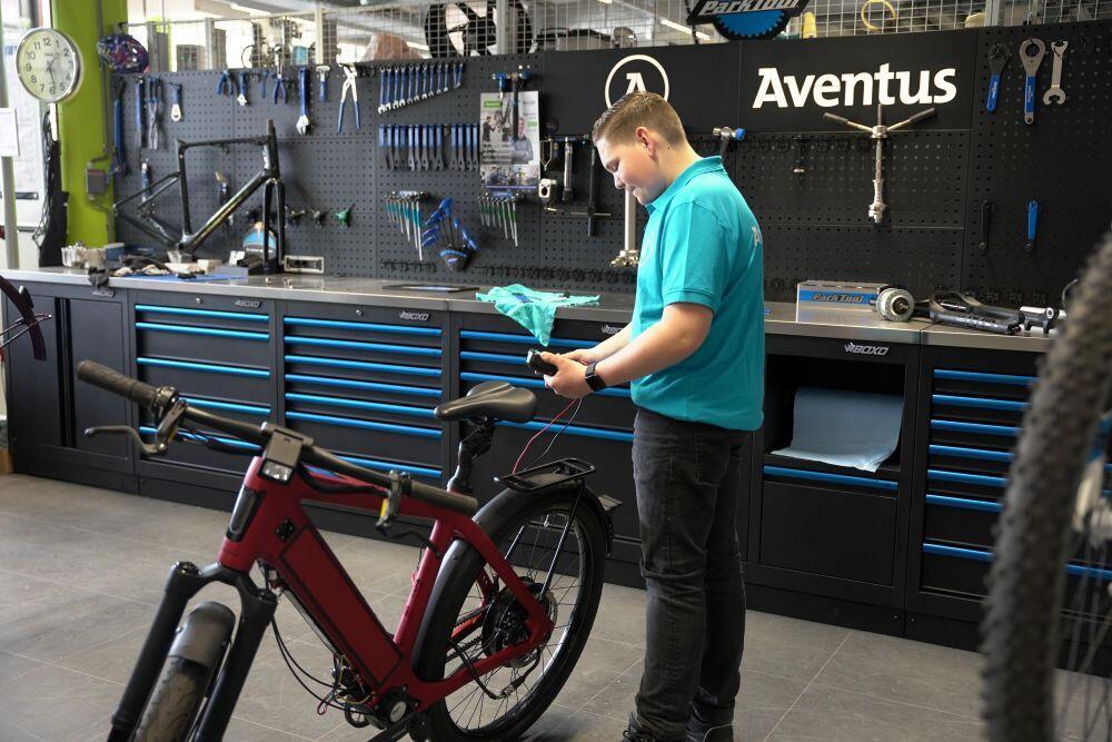 Een student Fietstechniek checkt de accu van een fiets in de praktijkruimte