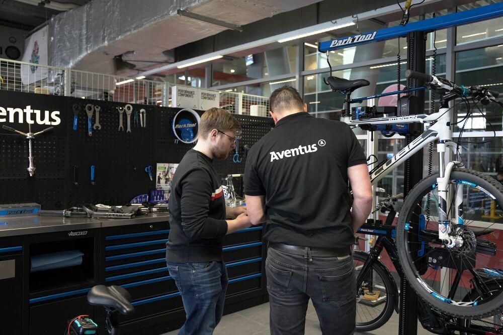 Een docent fietstechniek helpt een student met het repareren van een fiets