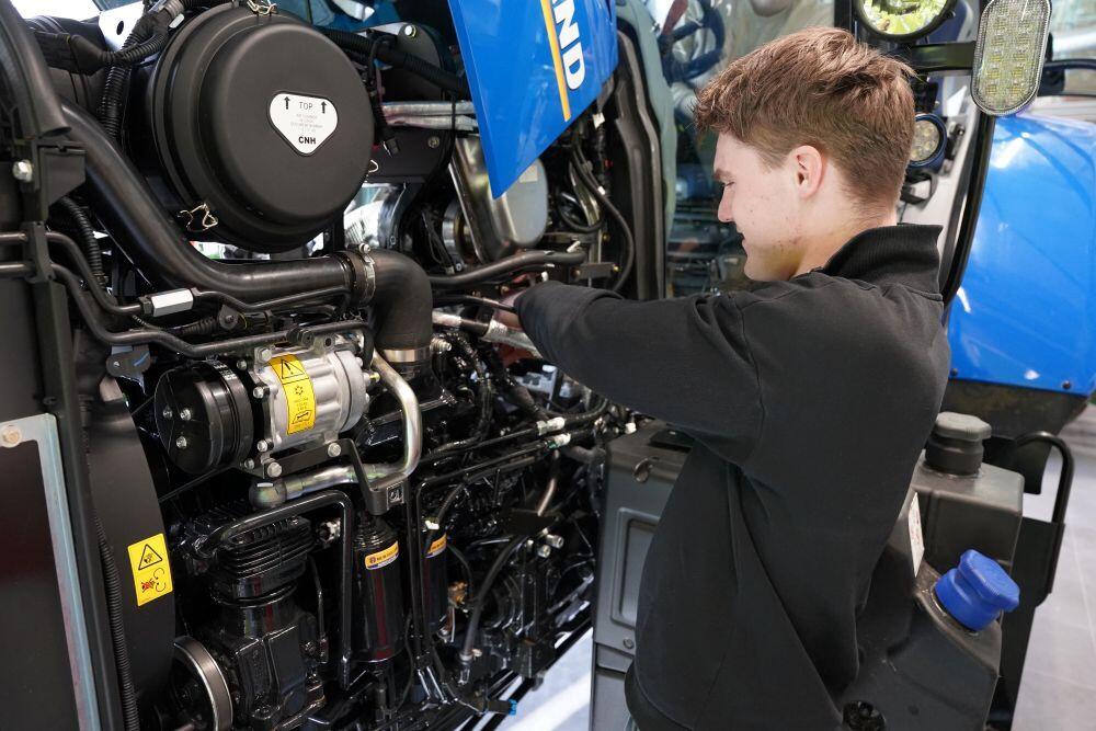 Een student Landbouwtechniek is bezig met de motor van een trekker