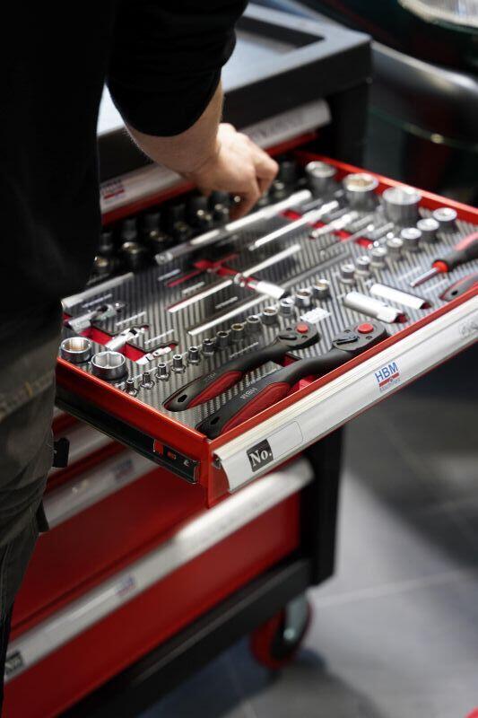 Een hand grijpt naar een gereedschap in een professionele toolbox