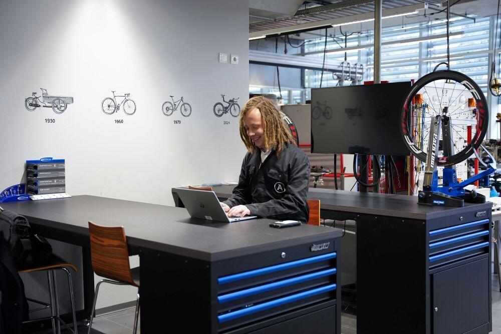 Een student Fietstechniek zit in de praktijkruimte achter zijn laptop