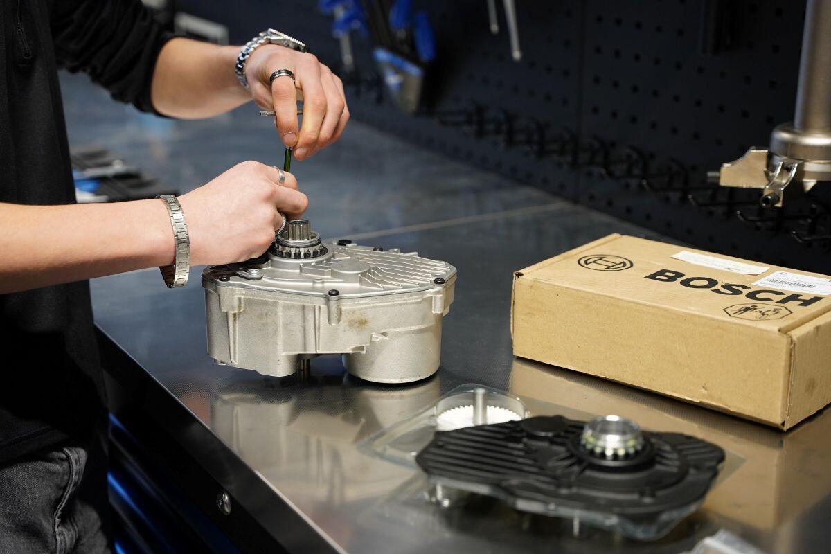 Een monteur werkt aan een klein motorblok dat op de werktafel ligt
