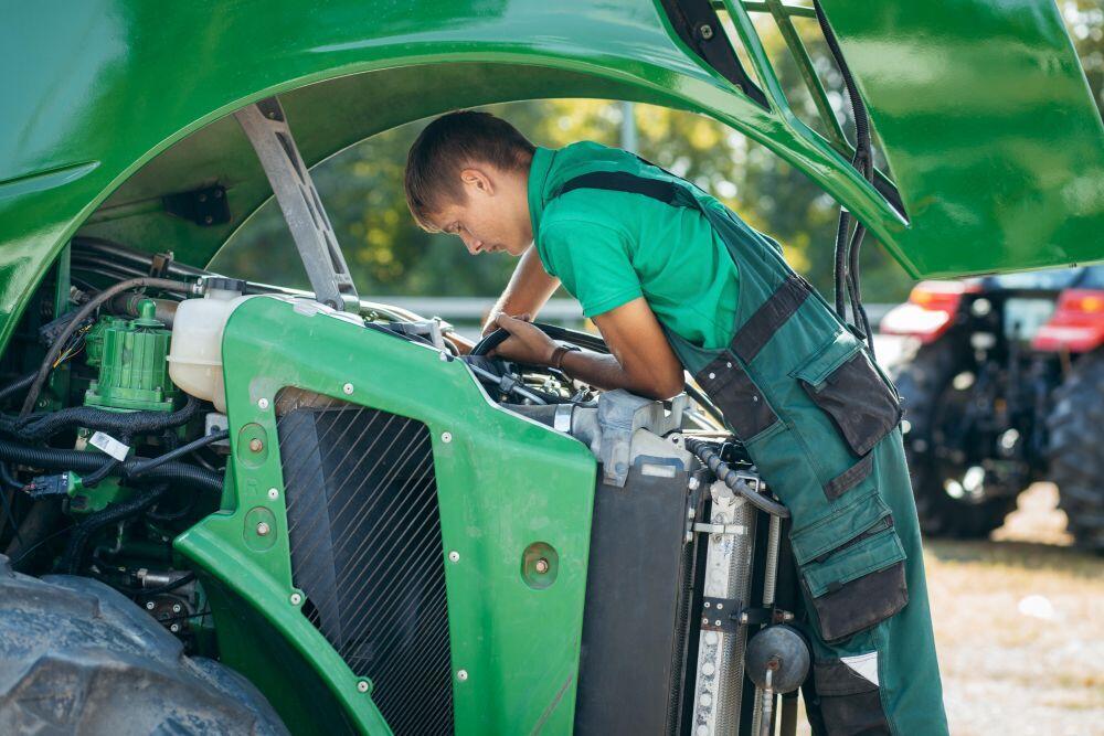 Een student Landbouwtechniek is bezig met de motor van een trekker