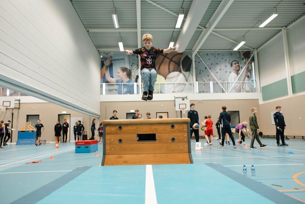 Een jongetje springt over een bok in de gymzaal