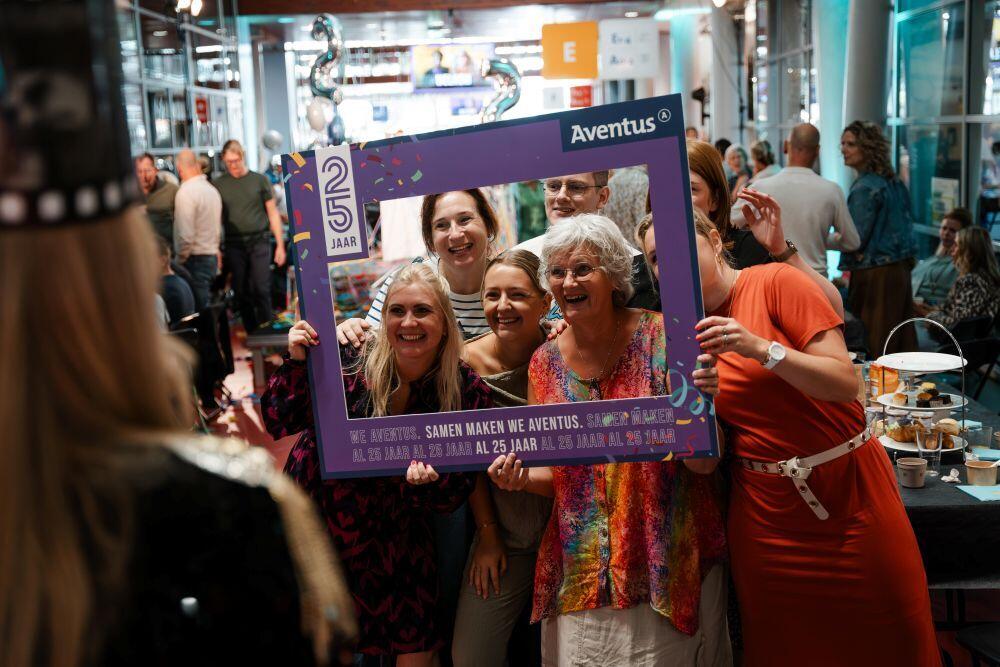 Aventus-medewerkers poseren voor een camera binnen een frame die ze zelf vasthouden 