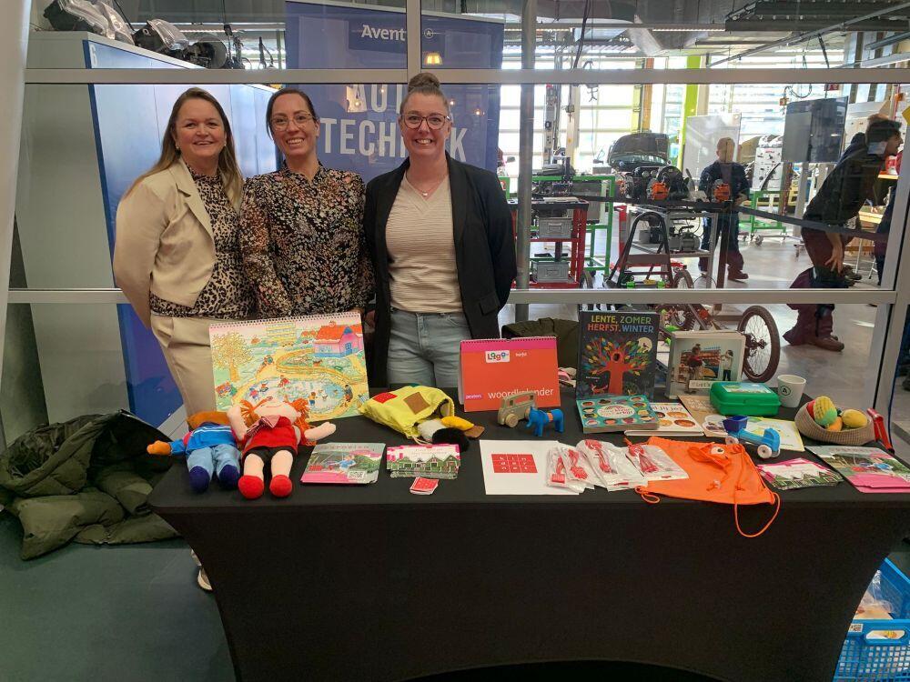 Drie medewerkers van een zorg- & welzijninstelling staan vrolijk achter hun stand in de Hi-street