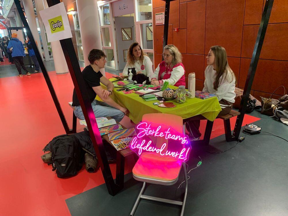 Vier personen zitten gezellig aan een tafel met allerlei promotiemateriaal