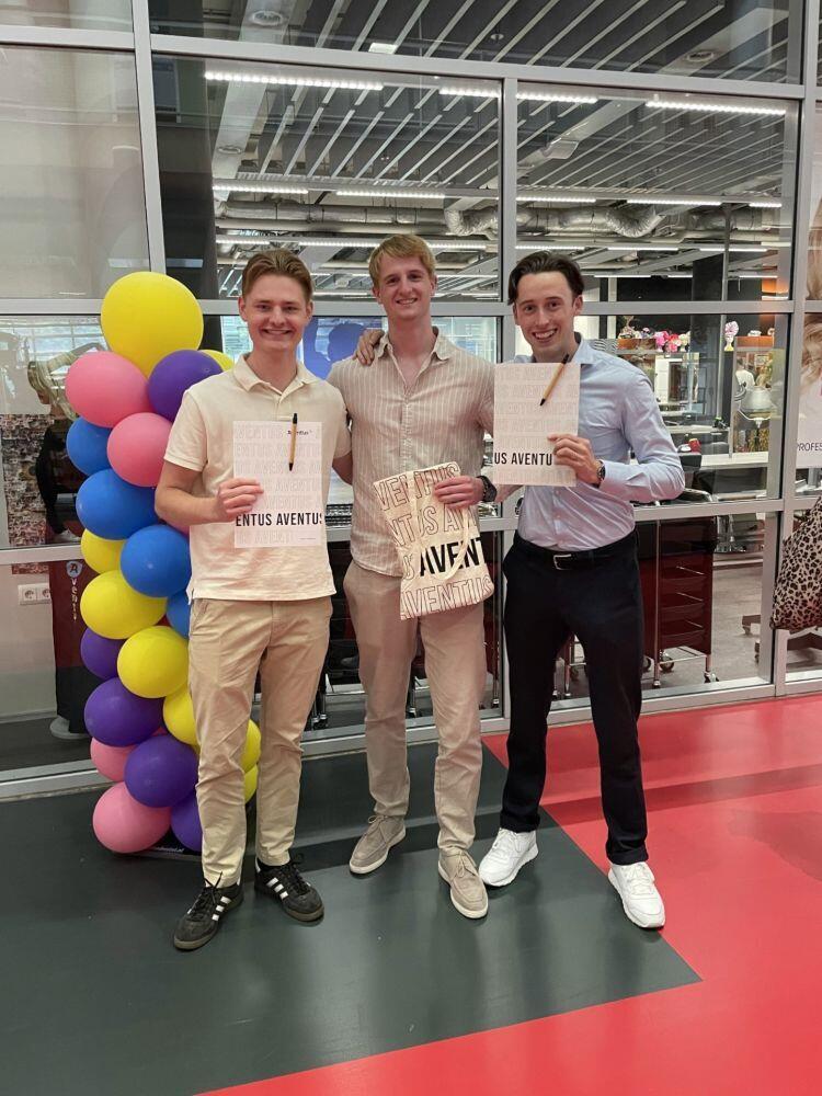 Drie studenten staan blij in de Hi-street met hun diploma in hun hand