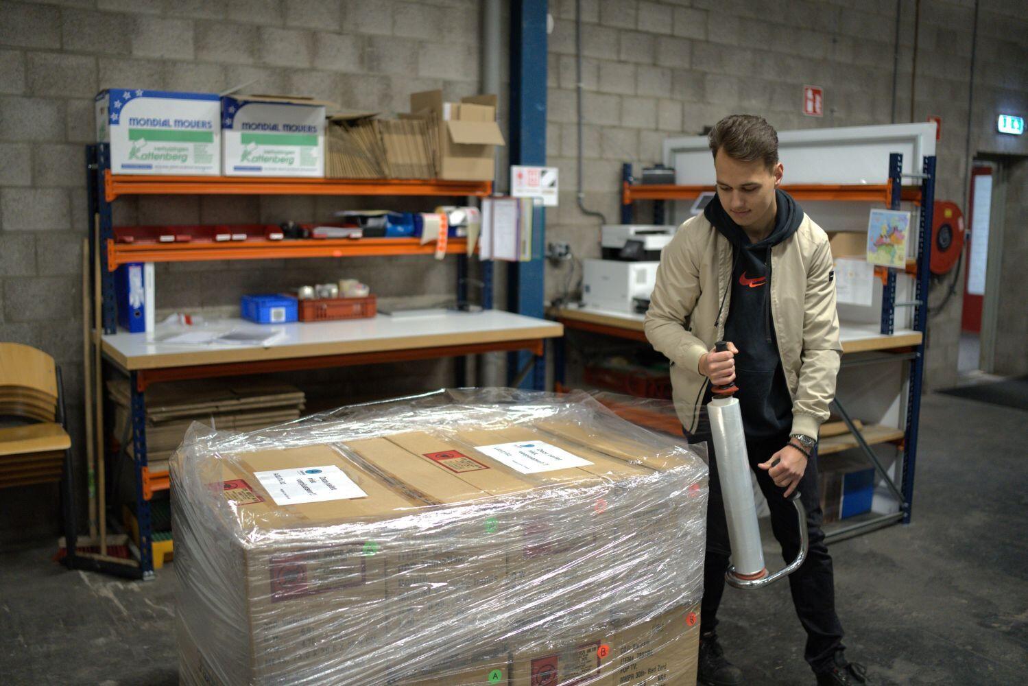 Jongeman wrapt plastic folie rond dozen op een pallet