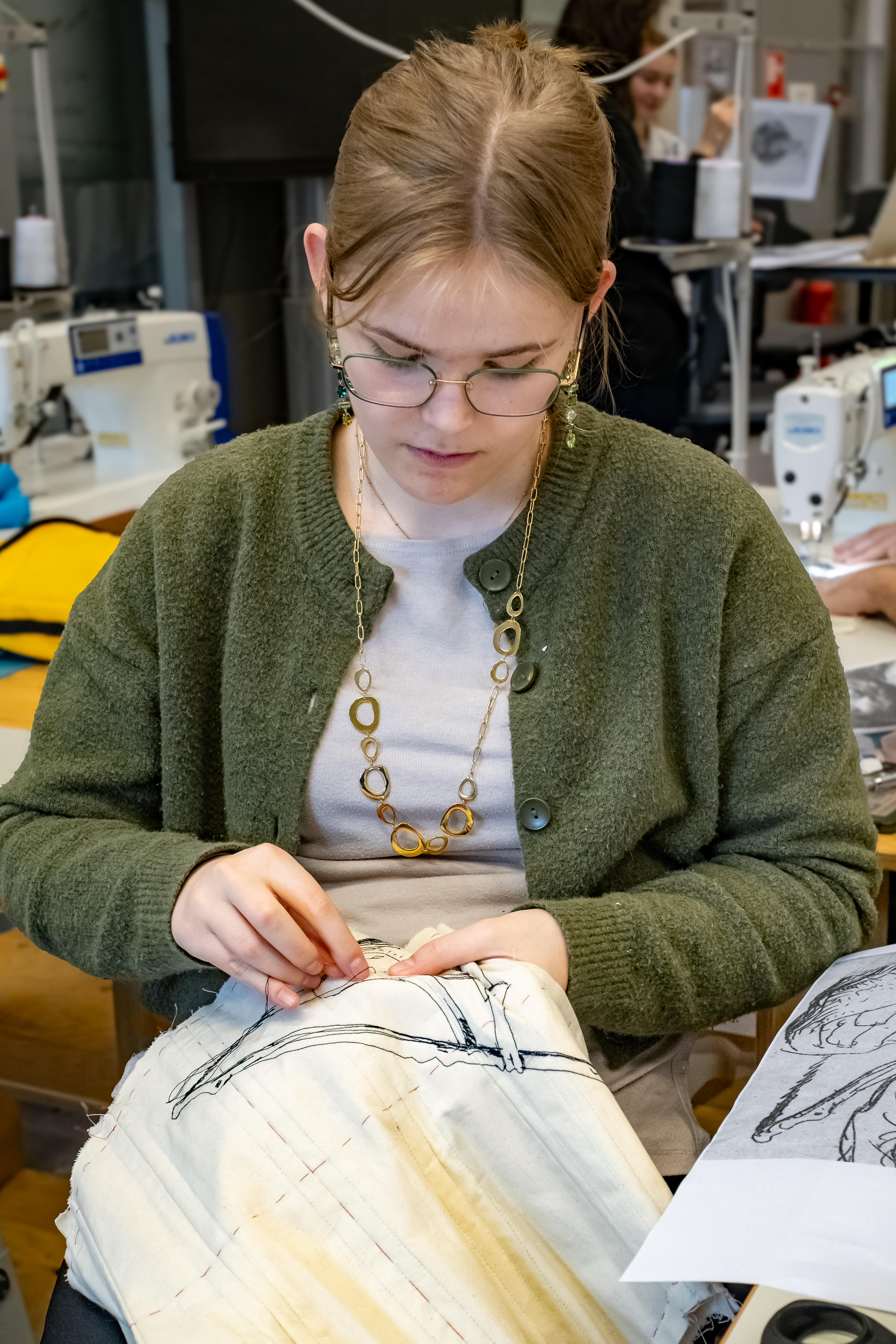 Fashion-studente borduurt een Rembrandt-ontwerp op een kledingstukmet 