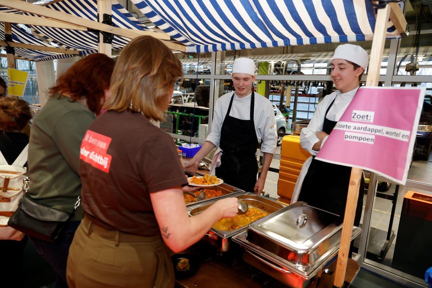 Twee deelnemers aan het symposium over gezonde jeugd staan bij het buffet