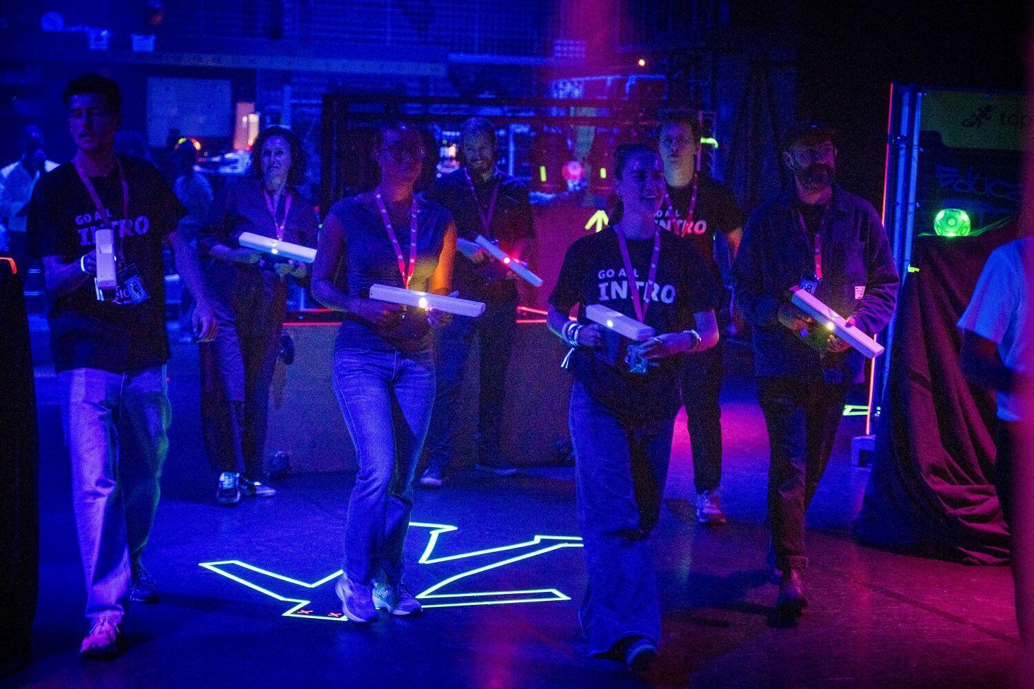 Een groep studenten staat met een lasergun in een donkere ruimte