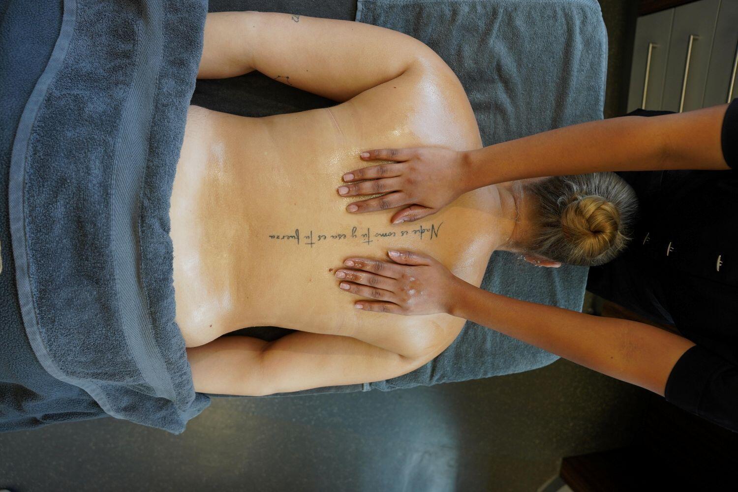 Twee handen masseren de rug van een klant