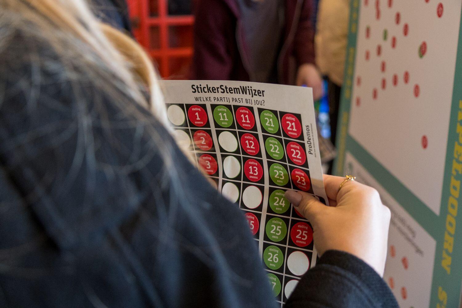 Studente met een stickervel bij de stickermuur 