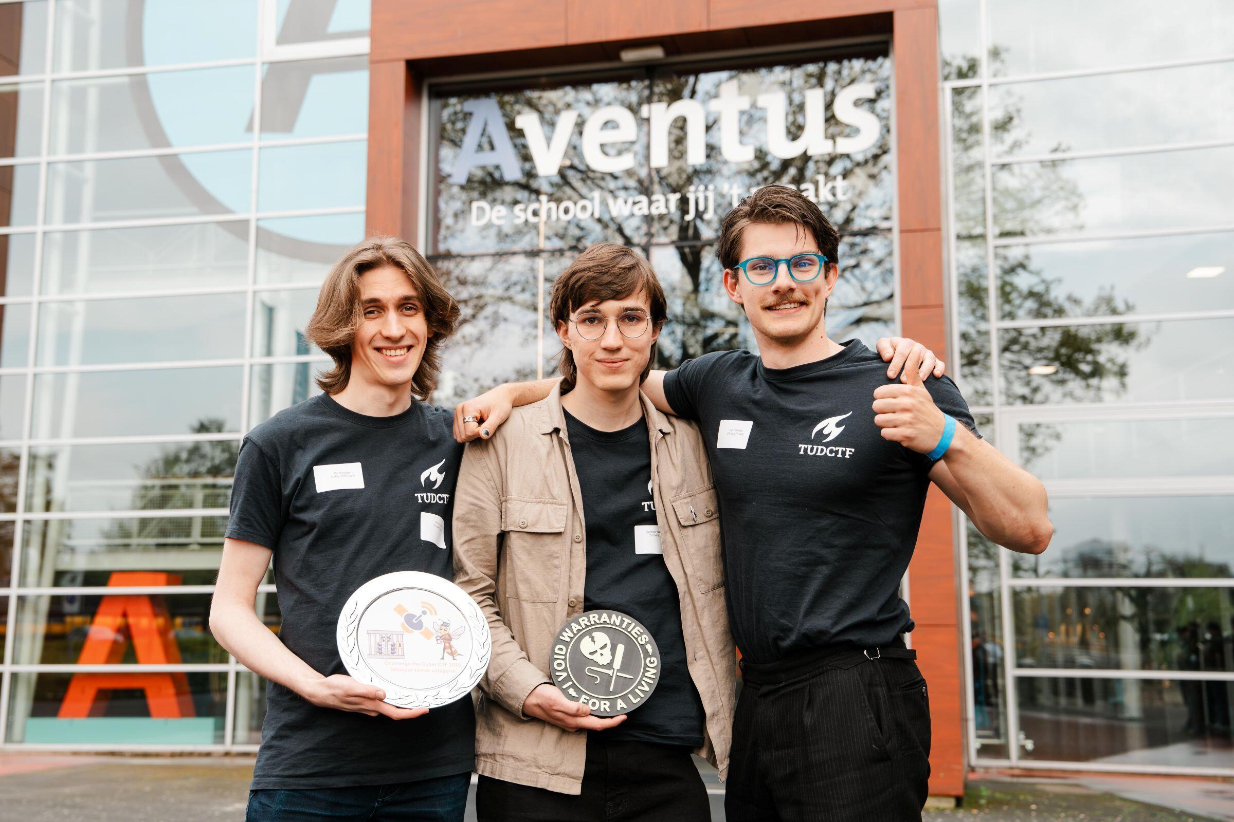 Drie studenten staan met hun Challenge the Cyber-prijs trots voor het Aventus-gebouw aan de Laan van de Mensenrechten