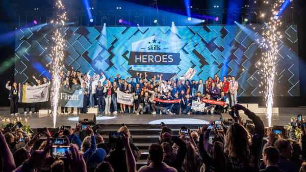 De winnaars van Skills Heroes staan op een podium met vuurwerk en worden toegejuicht door het publiek