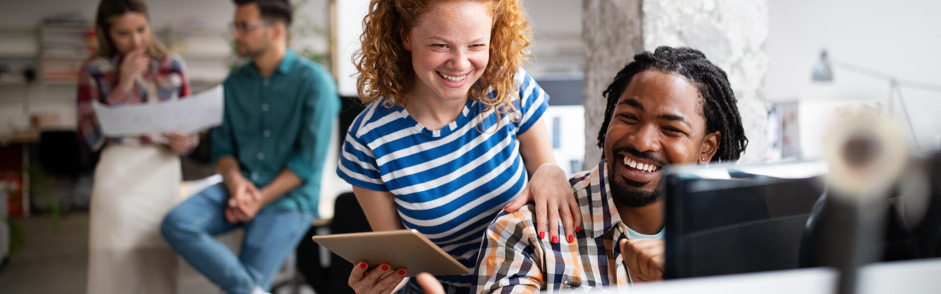 man en vrouw die lachend naar beeldscherm kijken 