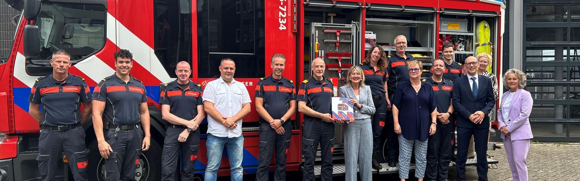 Ellen Marks poseert met een groep brandweermannen voor een bluswagen