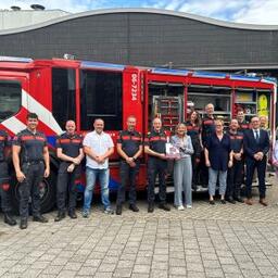 Ellen Marks poseert met een groep brandweermannen voor een bluswagen