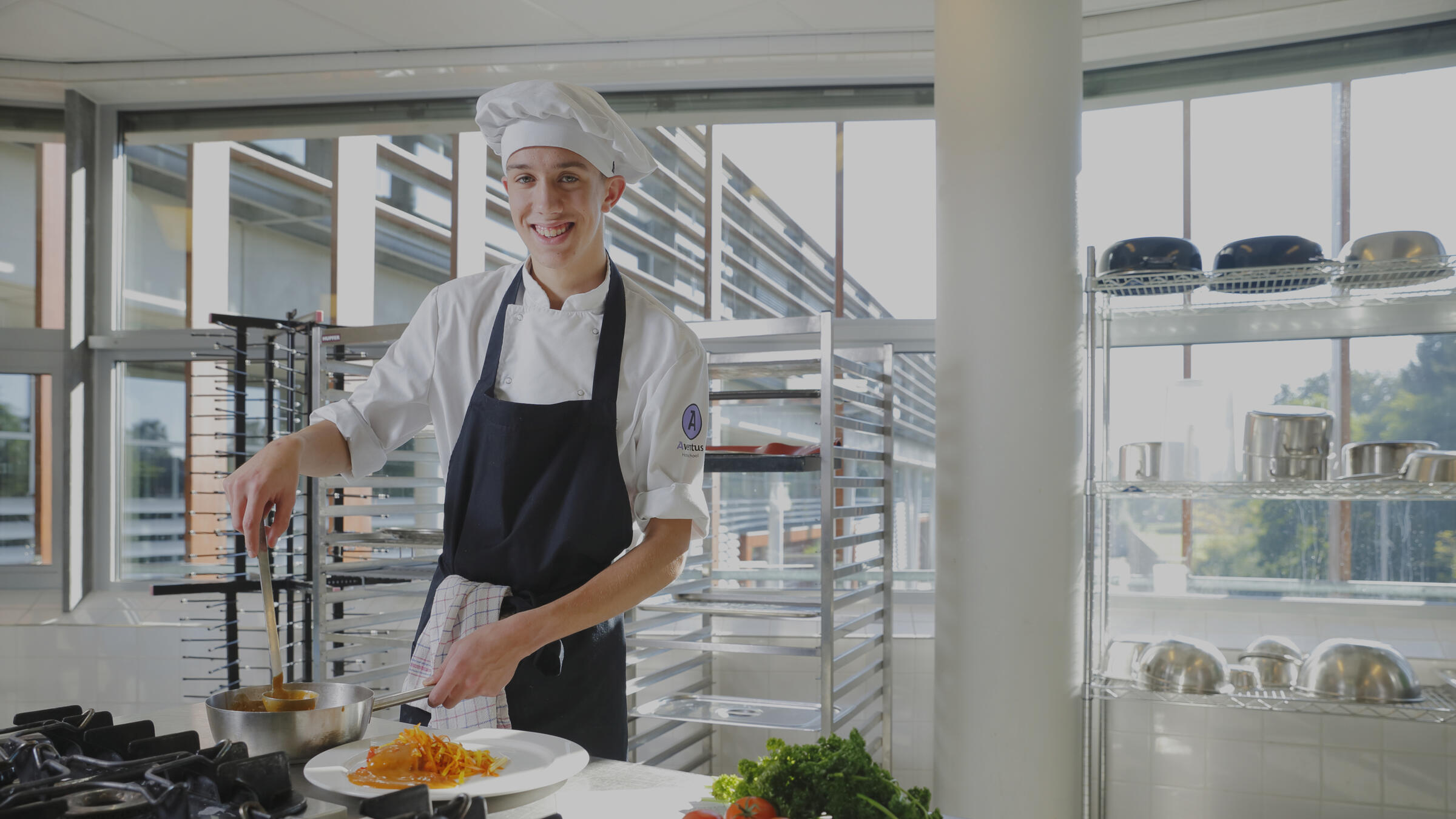 Een student kok staat vrolijk in de keuken